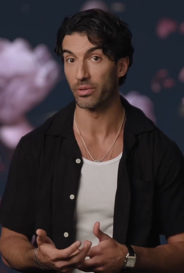 Man gesturing while discussing Ryan Reynolds texts in Justin Baldoni legal battle, wearing black shirt and white tank top.