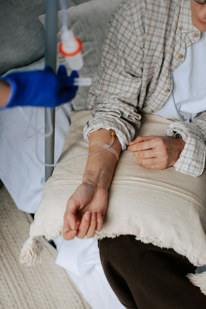Patient receiving intravenous treatment with a medical professional administering care in a clinical setting, illustrating bad prognosis cases.
