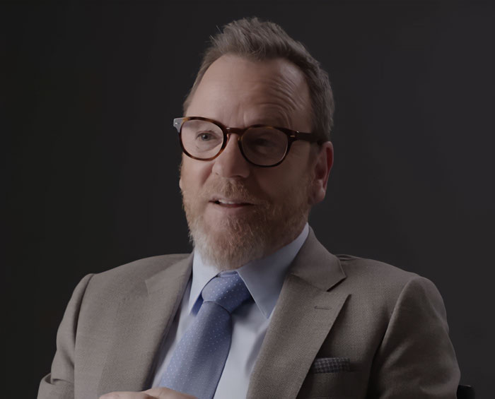 Middle-aged man with glasses and beard in a suit, discussing disturbing new details after violent crime arrest.