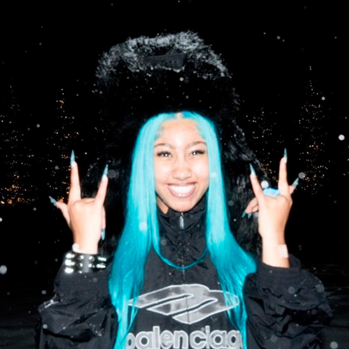 Young woman with bright blue hair and black fur hat smiling and making hand signs at night outdoors. Young woman with bright blue hair and black fur hat smiling and making hand signs at night outdoors.