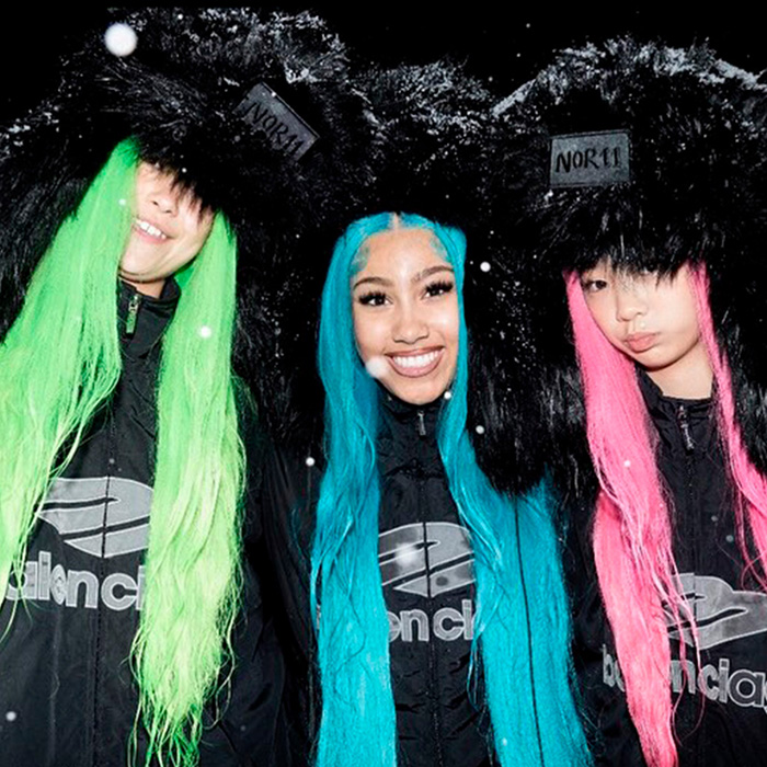 Three women wearing colorful wigs and black fur hats, styled fashionably amid winter snowfall, in a bold group look. Three women wearing colorful wigs and black fur hats, styled fashionably amid winter snowfall, in a bold group look.