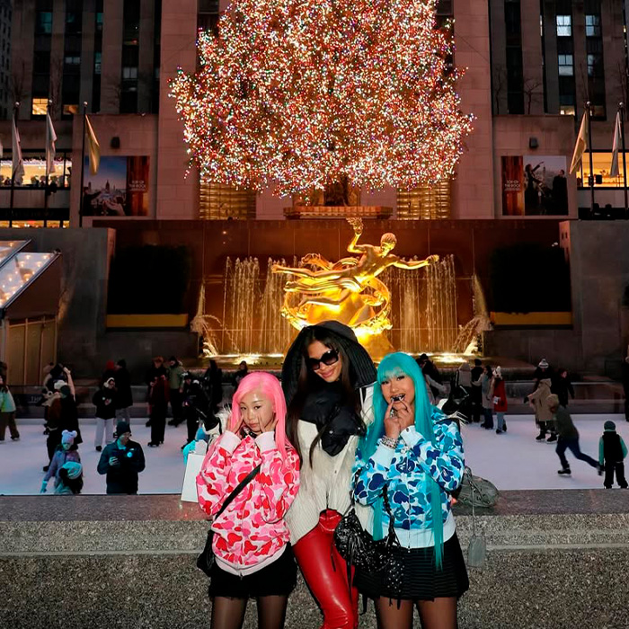 Three women posing in front of an illuminated Christmas tree and fountain, highlighting Kim Kardashian and North West interaction. Three women posing in front of an illuminated Christmas tree and fountain, highlighting Kim Kardashian and North West interaction.