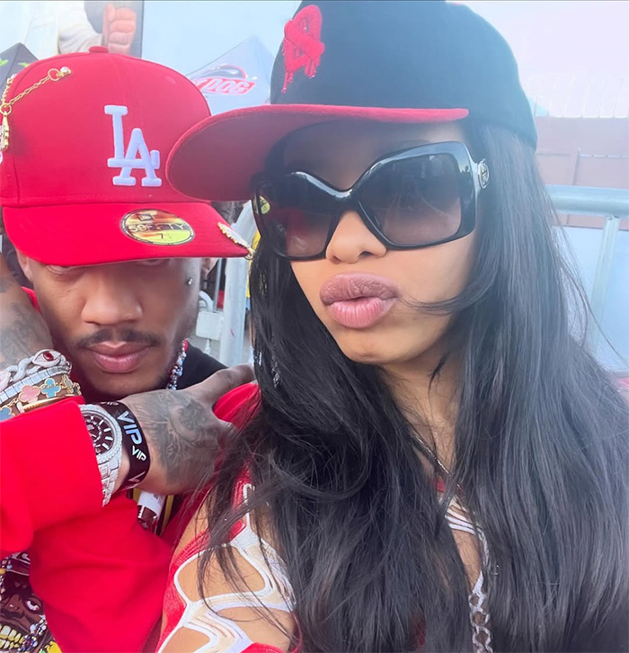 Two adults wearing red and black caps, with one person sporting large black sunglasses in an outdoor setting. Two adults wearing red and black caps, with one person sporting large black sunglasses in an outdoor setting.