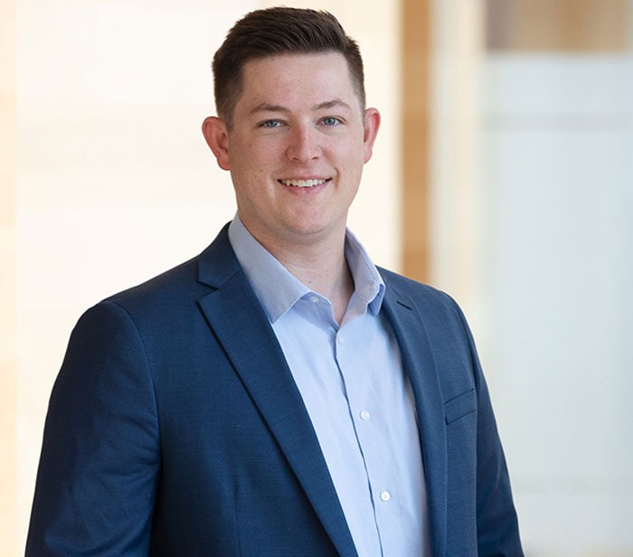 Young man in a blue suit smiling confidently in a bright, professional indoor setting, relating to teacher and student texts topic. Young man in a blue suit smiling confidently in a bright, professional indoor setting, relating to teacher and student texts topic.