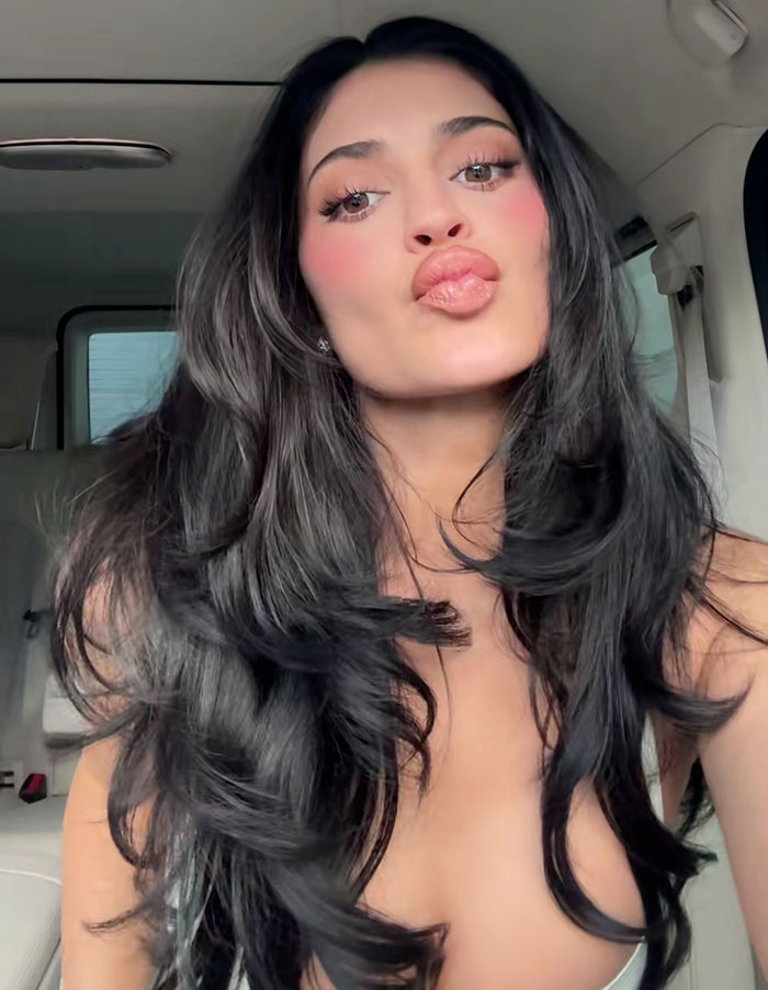 Kylie Jenner with long dark hair and glossy lips demonstrating her beauty hack involving botox for the Golden Globes.
