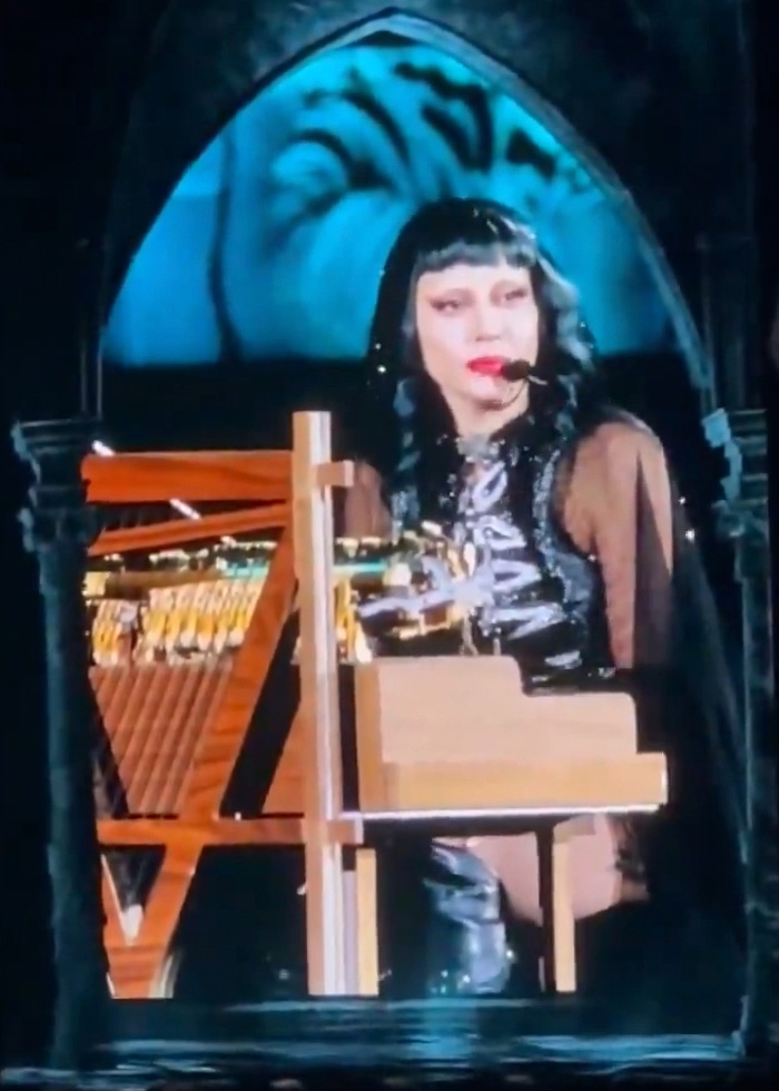 Lady Gaga performing at concert, wearing headset microphone and playing piano during bold ICE speech. Lady Gaga performing at concert, wearing headset microphone and playing piano during bold ICE speech.