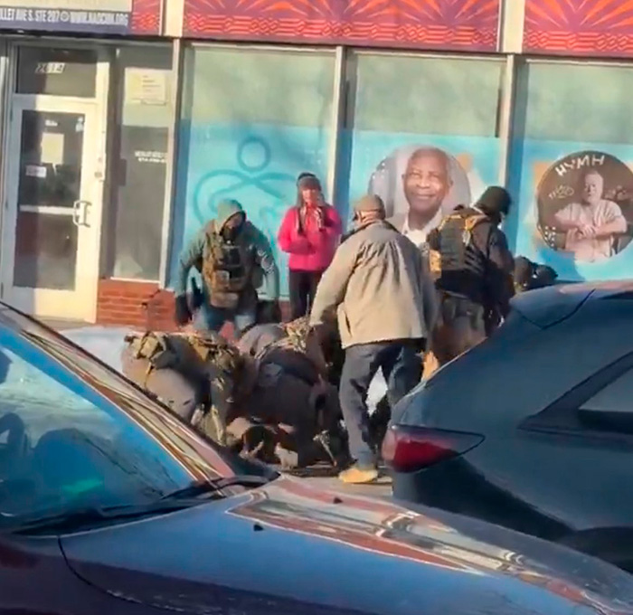 A group of people wearing tactical gear arresting a person on the street, related to ICE enforcement action. A group of people wearing tactical gear arresting a person on the street, related to ICE enforcement action.