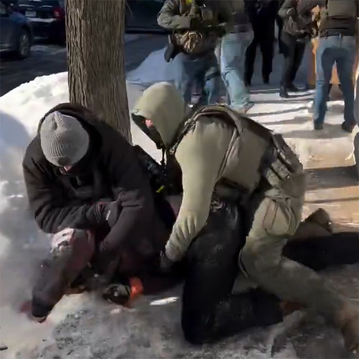 Two people on a snowy street with one person restraining another, related to a bold ICE speech incident. Two people on a snowy street with one person restraining another, related to a bold ICE speech incident.