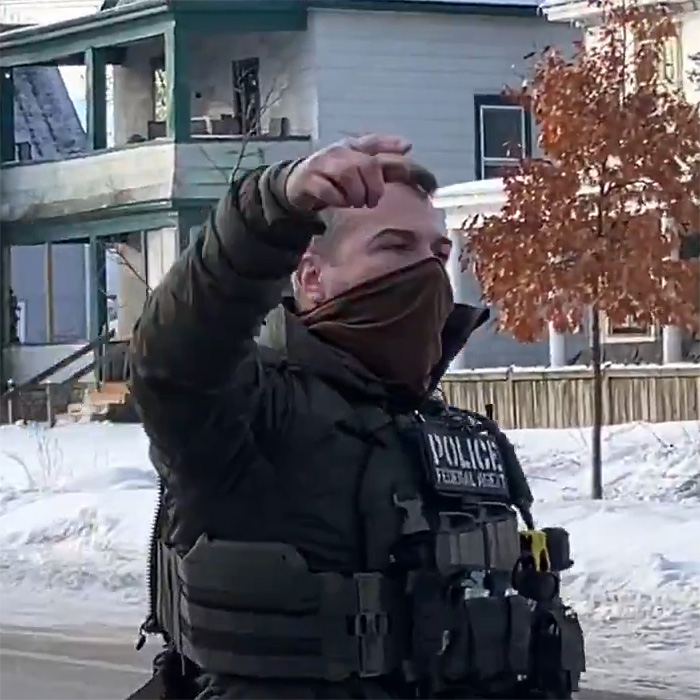 Police officer in tactical gear and face covering outside near houses and snow, related to bold ICE speech incident. Police officer in tactical gear and face covering outside near houses and snow, related to bold ICE speech incident.