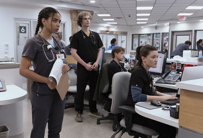 Hospital staff in scrubs at nurses station, depicting Pitt fans dragging new Season 2 addition amid potential romance.