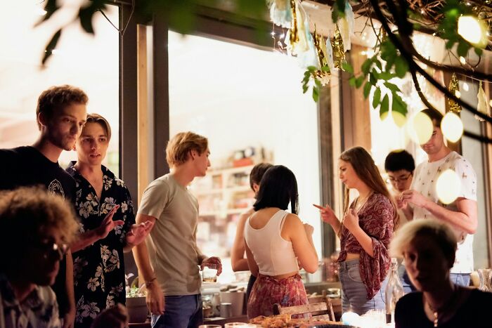 Group of people socializing at a lively gathering, illustrating cultural differences and things normal in their country but offensive elsewhere.