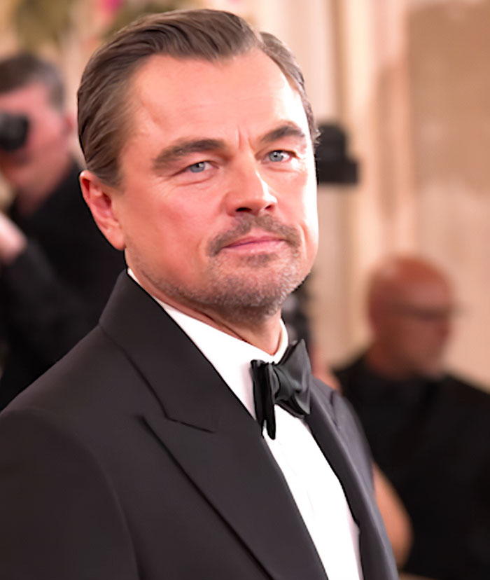 Leonardo DiCaprio in a black tuxedo at the Golden Globes, involved in a viral sassy exchange revealed by a lip reader.