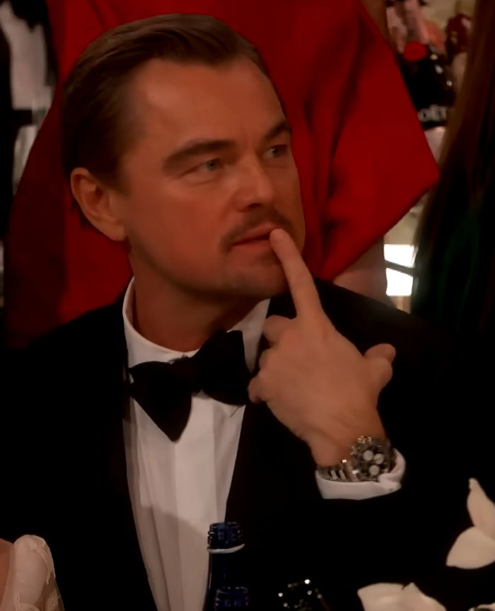 Leonardo DiCaprio at the Golden Globes wearing a tuxedo, making a sassy gesture during a viral exchange.