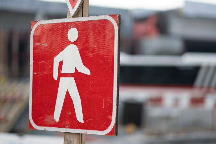 Red pedestrian crossing sign on wooden post highlighting cultural differences in what is normal or offensive worldwide.