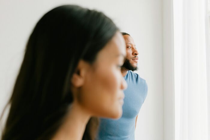 A thoughtful man and woman standing indoors near a window, reflecting on surprising DNA test results and family discoveries.