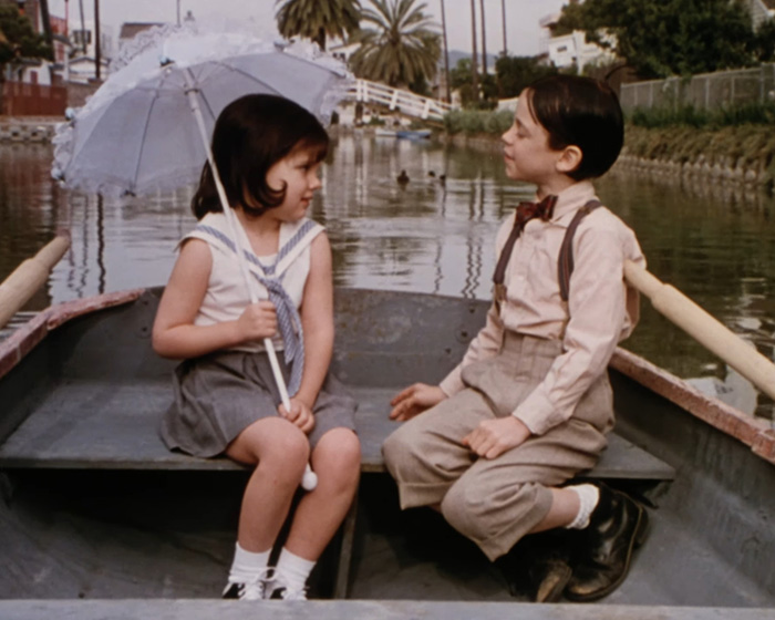 Two children dressed in vintage clothing sitting in a boat near a canal, reflecting Little Rascals star living off the grid. Two children dressed in vintage clothing sitting in a boat near a canal, reflecting Little Rascals star living off the grid.