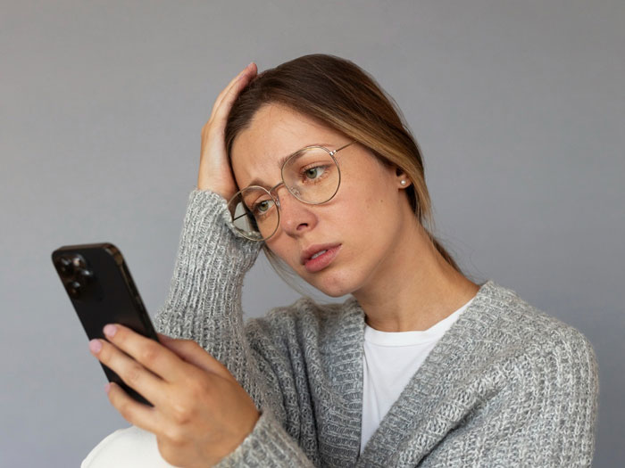 Worried woman in glasses reading phone, reflecting on man jumping into hero mode for pregnant ex and baby care.