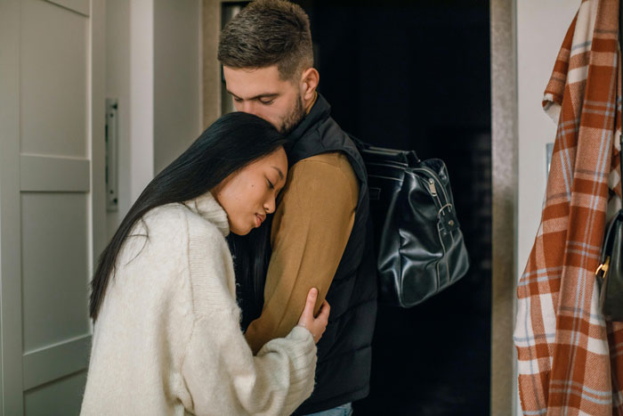 Man comforting pregnant ex with a hug, showing support while standing in a cozy home setting.