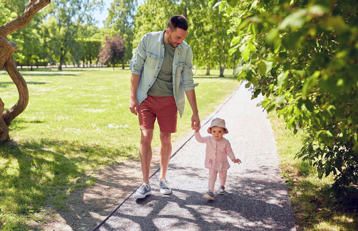 Man walking with toddler in park, symbolizing man jumps into hero mode for pregnant ex and raising her baby.