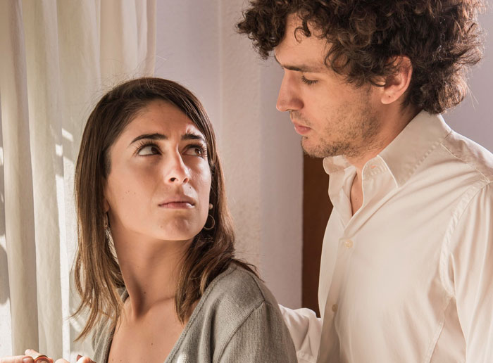 Man offers to raise pregnant ex's baby while girlfriend walks away, showing tension between the couple in a domestic setting.