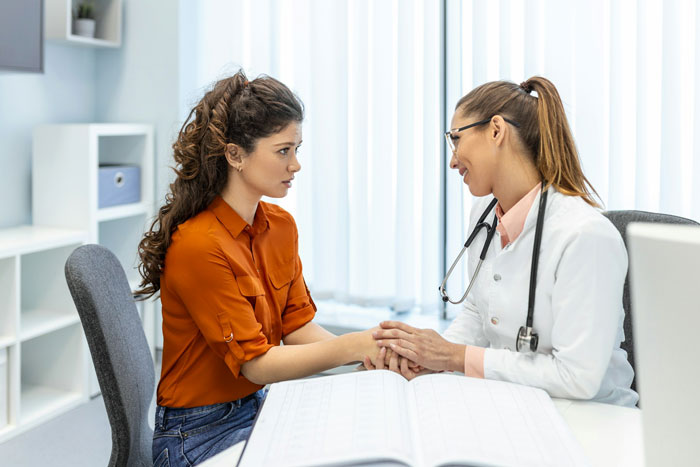 Teen and doctor having a serious conversation in a medical office, representing teen forced to marry 32YO situation.