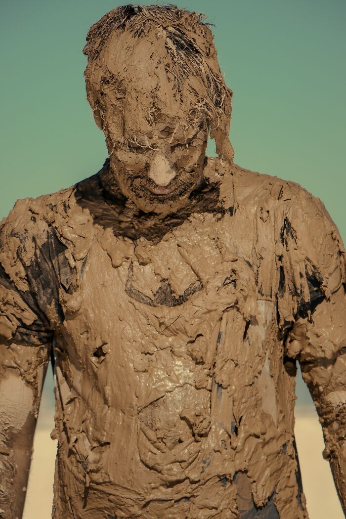 Person covered in thick mud from head to torso, illustrating 3 AM chaos during the night shift work challenges.