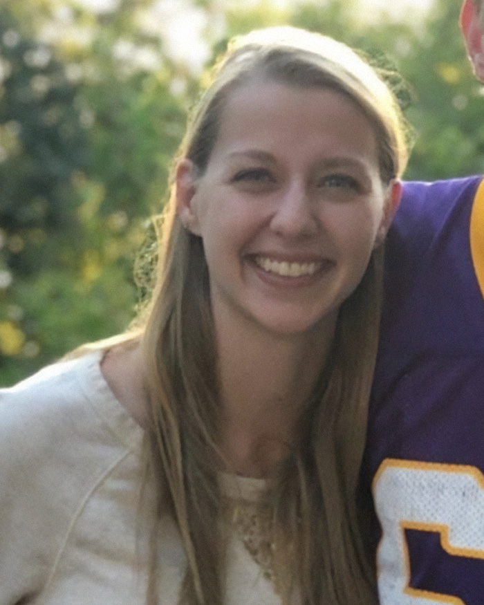 Young woman smiling outdoors with blurred trees in the background related to pregnant sister homicide news.