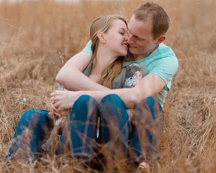 Young couple embracing in a dry field, unrelated to man admitting horrific charges over pregnant sister&rsquo;s homicide.