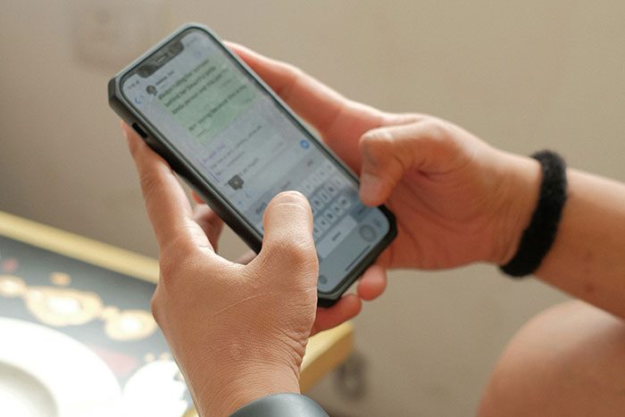 Person holding a smartphone, typing a message about family deciding to forgive man for past conflict.