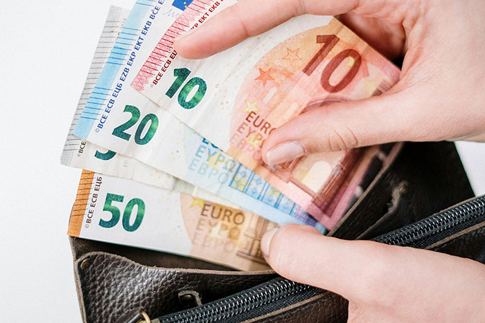 Hands holding euro bills above a purse, illustrating gf's ATM metaphor for financial dependence