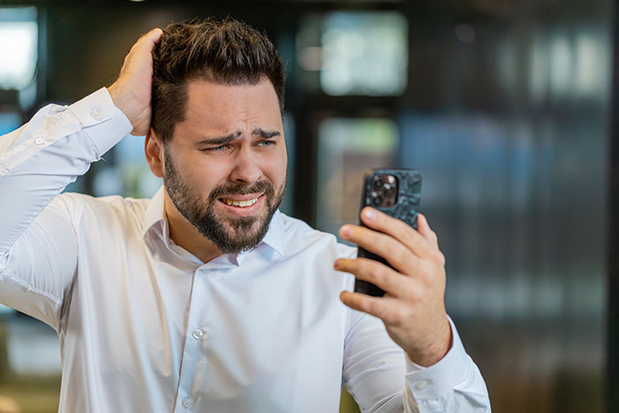 Man confused and frustrated looking at phone, representing guy ditched after refusing to pay thousands on two dates.