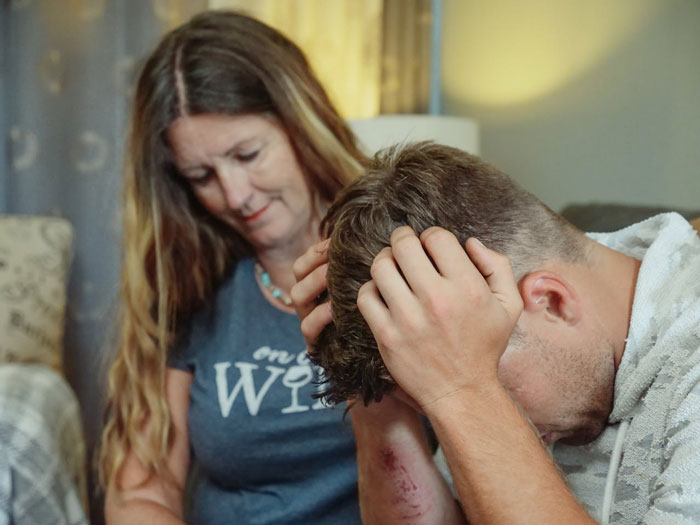 Woman looking at a young man holding his head, depicting tension over secretly going through girlfriend’s wallet and ID.
