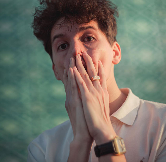 Young man looking disturbed, covering his mouth with hands, reflecting emotional reaction to secret wallet search and ID photos.