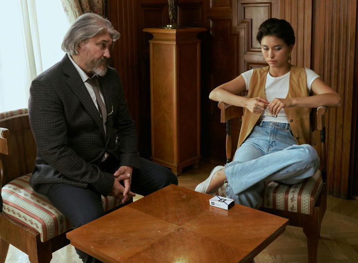 Older man and young woman sitting apart in a tense room, reflecting guilt and distance during a messy divorce situation.