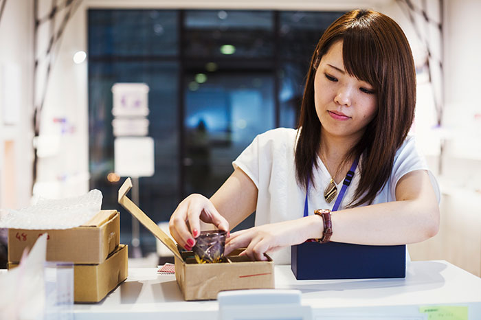 Young woman packing items into boxes at desk, symbolizing reckoning and revenge in a coworker conflict resolution.