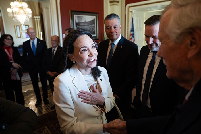 Nobel Committee members engaged in discussion after peace prize recipient gifts her medal to Trump in formal setting.