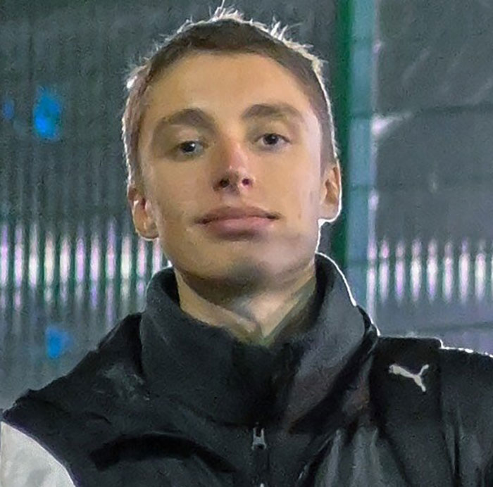Young man in a black Puma jacket standing outdoors at night, related to Barron Trump emergency call challenged by judge.