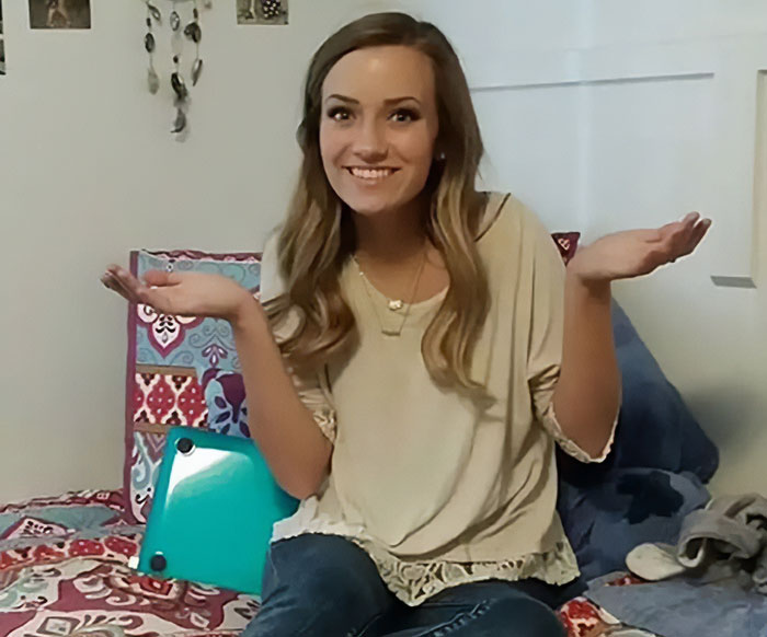 Young woman sitting on bed with laptop, smiling and raising hands, representing bold texts from teacher to student incident. Young woman sitting on bed with laptop, smiling and raising hands, representing bold texts from teacher to student incident.