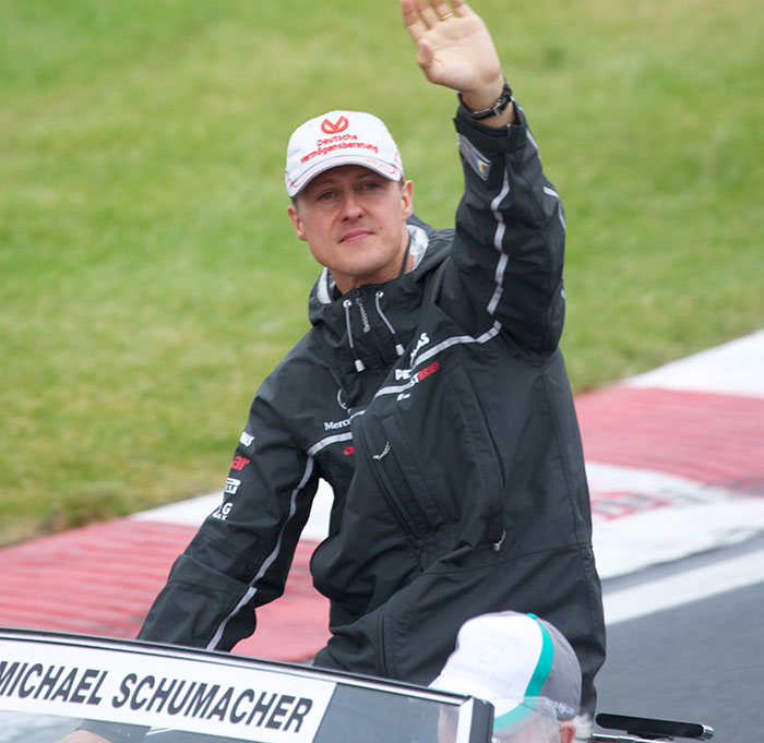 Michael Schumacher waving to fans at a motorsport event, related to major health update after accident.