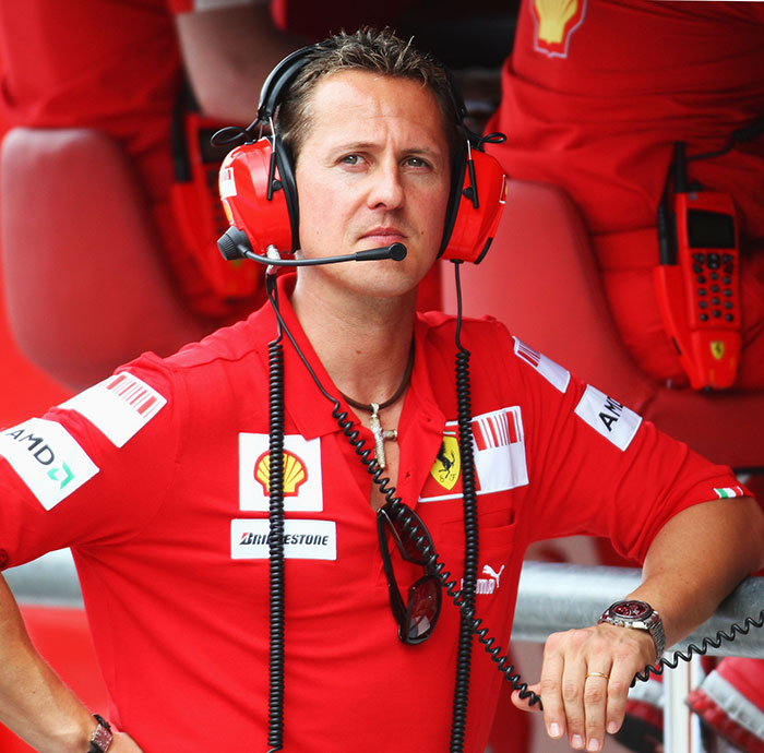 Michael Schumacher wearing Ferrari team gear and headset during a Formula 1 race, related to his health update.