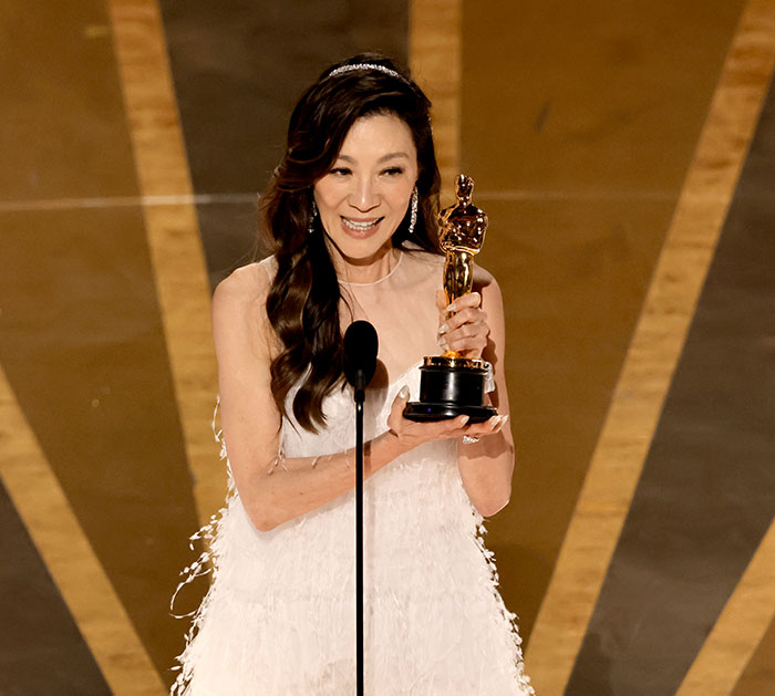 Female celebrity holding an award trophy onstage following strict rules at an award show ceremony.