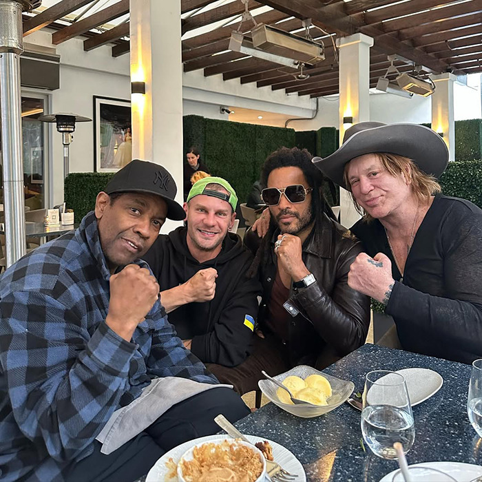 Group of four men posing with fists raised at a restaurant, unrelated to Mickey Rourke eviction or unpaid rent.