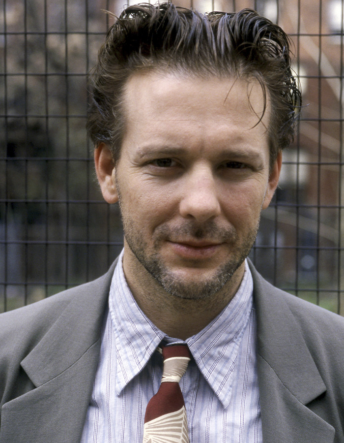 Mickey Rourke in a suit and patterned tie, facing eviction from LA home over $60K unpaid rent issue.