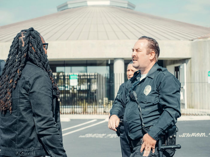 Police officer in uniform confronting a woman outside a building during family drama involving violent behavior. Police officer in uniform confronting a woman outside a building during family drama involving violent behavior.