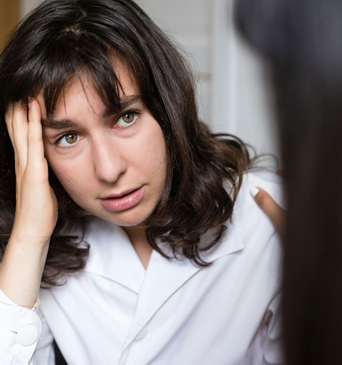 Woman looking stressed and frustrated during a tense conversation with her controlling vegan friend indoors.