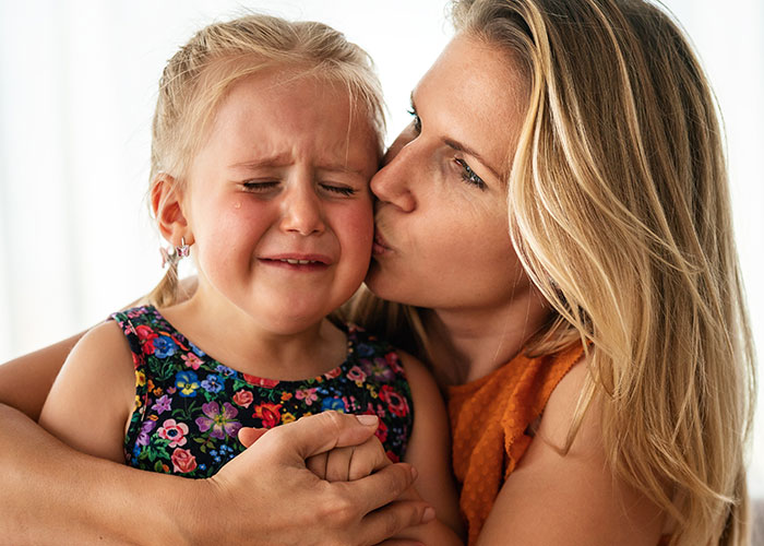 Mother comforting crying daughter during emotional moment as mil tells kids parents passed away in a heartfelt scene.