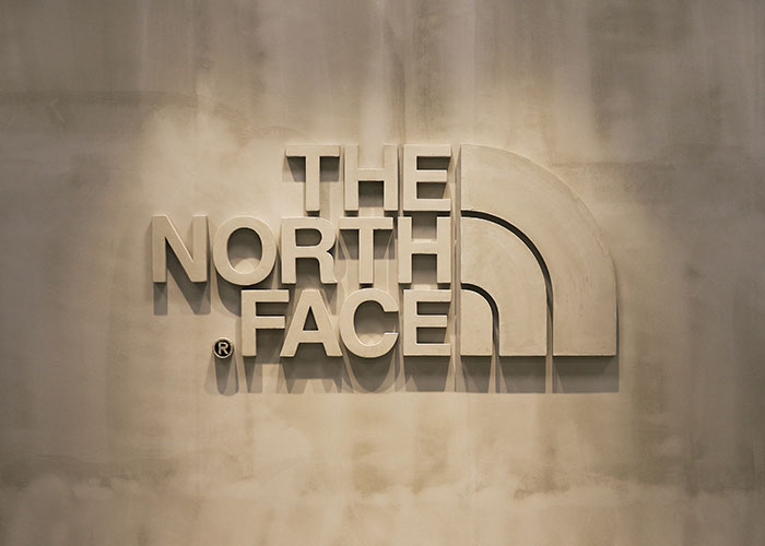 The North Face logo mounted on a textured wall, showcasing outdoor and adventure branding design.