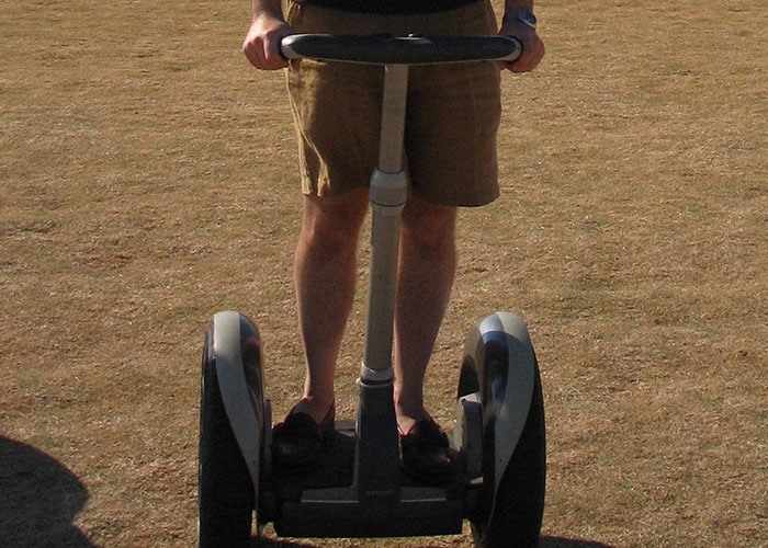 Person riding a Segway on dry grass, illustrating one of the ironic ways people passed away unexpectedly.