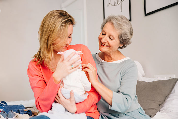 Mother and grandmother smiling at newborn baby, illustrating family moments related to mil-refuse-baby-name issues.