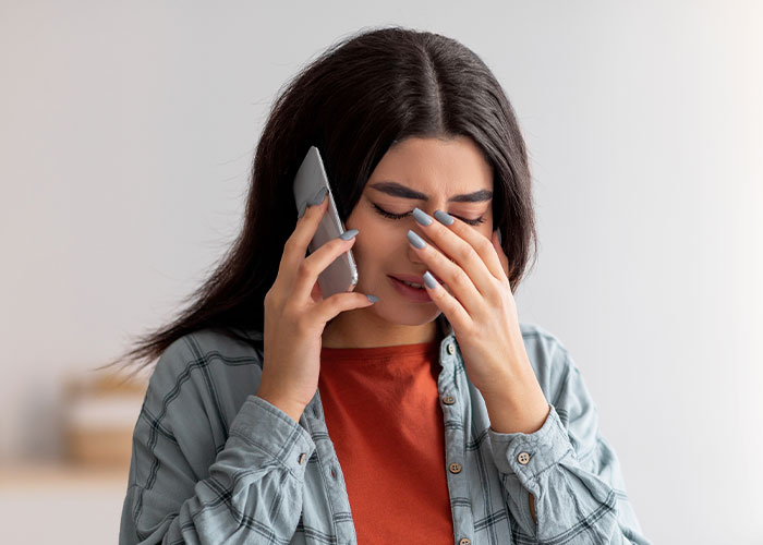 Young woman upset while on a phone call, reflecting emotional distress related to mom blaming daughter in divorce conflict.